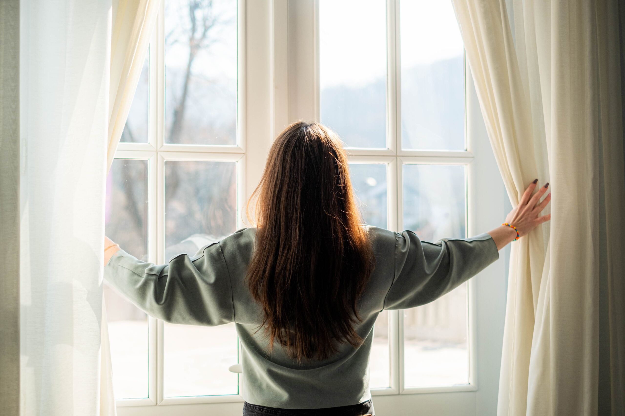Psychotherapie bei Ängsten und Depressionen mit Frau am Fenster im Morgenlicht 
